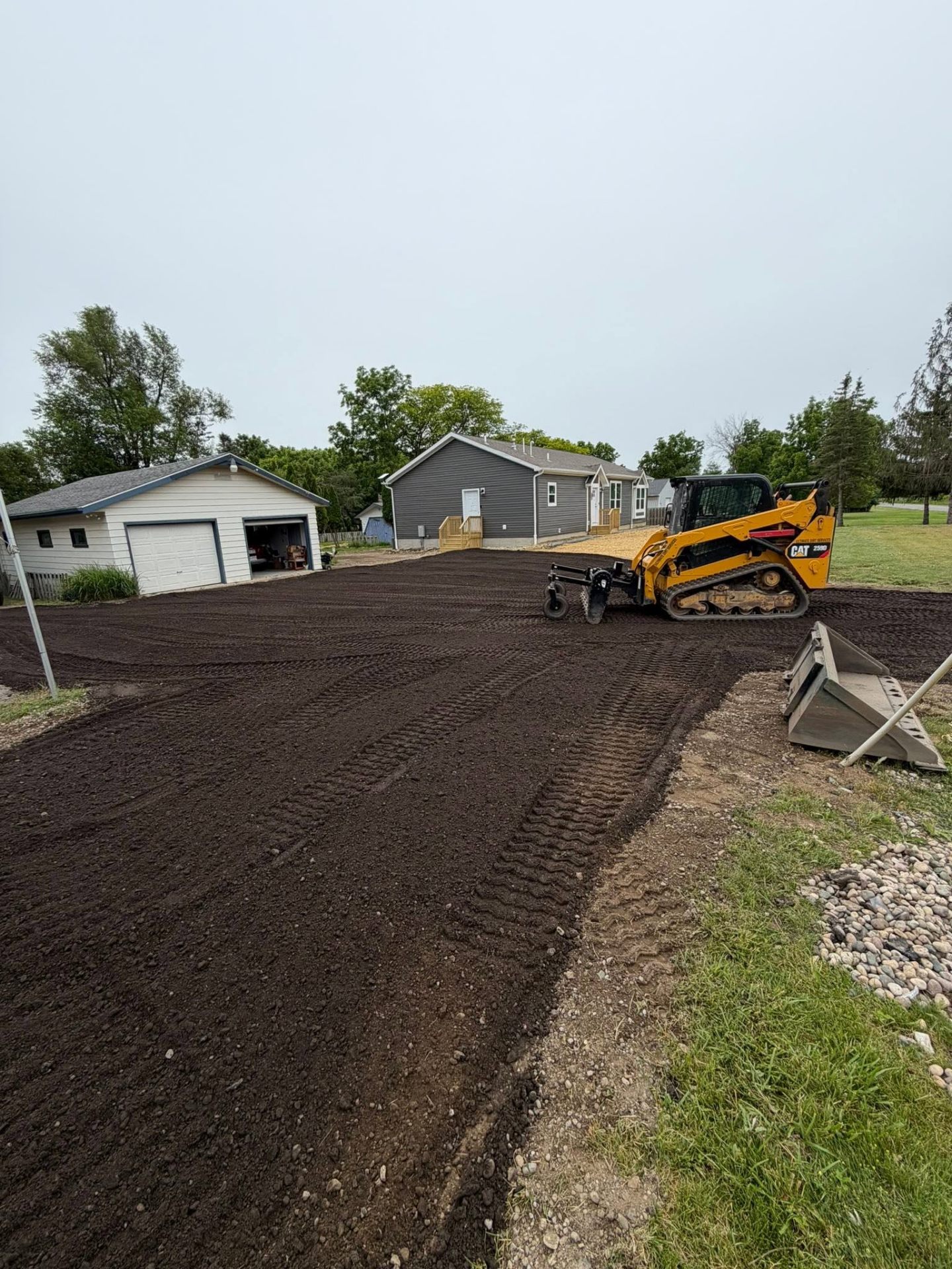 Skid steer grading a fresh gravel driveway in Jackson, MI